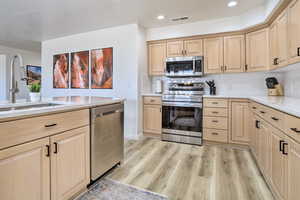 Kitchen featuring decorative backsplash, appliances with stainless steel finishes, light brown cabinetry, sink, and light hardwood / wood-style flooring