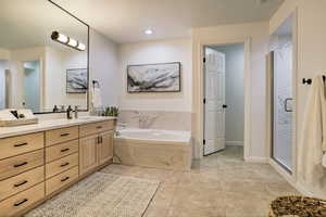 Bathroom with tile patterned flooring, vanity, and separate shower and tub