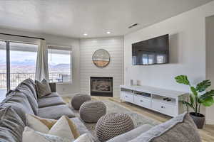 Living room featuring a large fireplace, light hardwood / wood-style floors, and a textured ceiling