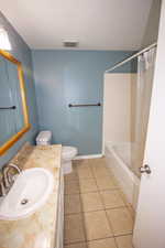 Full bathroom with tile patterned flooring, vanity, toilet, and shower / tub combo with curtain