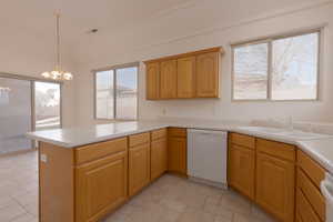 Kitchen featuring kitchen peninsula, sink, pendant lighting, dishwasher, and a chandelier