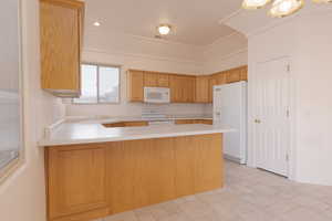 Kitchen with sink, white appliances, and kitchen peninsula