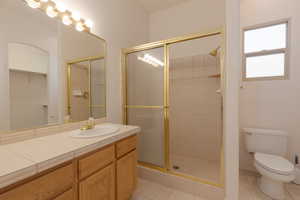 Bathroom with tile patterned floors, a shower with door, vanity, and toilet