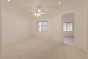 Carpeted spare room with ceiling fan with notable chandelier and ornamental molding