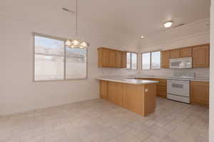 Kitchen with an inviting chandelier, kitchen peninsula, crown molding, decorative light fixtures, and white appliances