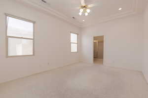 Empty room featuring a tray ceiling, ceiling fan, and light colored carpet