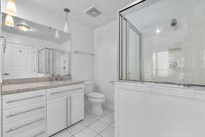 Bathroom featuring tile patterned flooring, vanity, toilet, and a shower with shower door