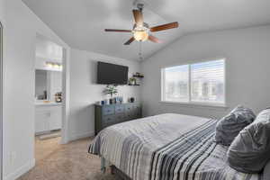 Bedroom featuring ensuite bath, ceiling fan, light carpet, and lofted ceiling