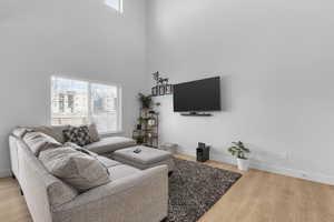 Living room featuring a healthy amount of sunlight, a high ceiling, and hardwood / wood-style flooring