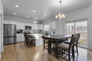 Dining space with a chandelier, light hardwood / wood-style floors, a wealth of natural light, and sink