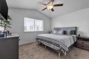 Carpeted bedroom with ceiling fan and vaulted ceiling