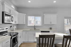 Kitchen featuring appliances with stainless steel finishes, light hardwood / wood-style floors, white cabinetry, and sink