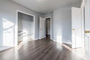 Unfurnished bedroom/office with dark hardwood / wood-style floors and a closet.