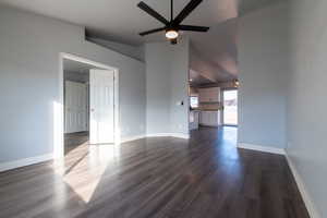 Unfurnished living room featuring dark hardwood / wood-style floors, ceiling fan, and lofted ceiling