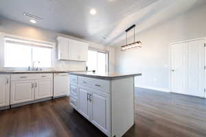 Kitchen with a center island, dishwasher, decorative light fixtures, lofted ceiling, and white cabinets