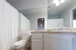 Primary bathroom with tasteful backsplash, vanity, tile walls, and toilet