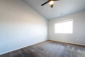 Primary bedroom featuring ceiling fan, carpet, and lofted ceiling