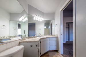 Primary bathroom with tile patterned floors, vanity, toilet, and walk in shower