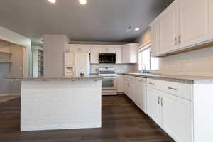 Kitchen with a center island, white appliances, sink, and white cabinetry