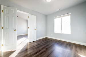 Unfurnished bedroom/office featuring dark wood-type flooring