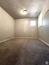 Empty room with carpet floors and a textured ceiling