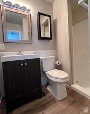 Bathroom with hardwood / wood-style floors, vanity, toilet, and a shower