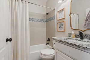 Full bathroom featuring vanity, toilet, and shower / tub combo with curtain