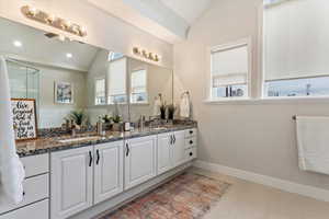 Bathroom with tile patterned flooring, vanity, and lofted ceiling