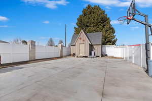 View of patio / terrace featuring basketball hoop and a storage shed