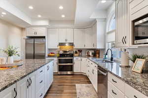 Kitchen with sink, white cabinets, stainless steel appliances, and stone countertops