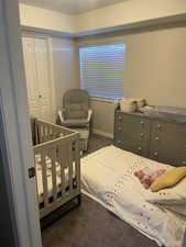 Carpeted bedroom with a closet and a crib