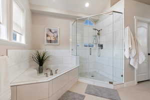 Bathroom with shower with separate bathtub and tile patterned floors