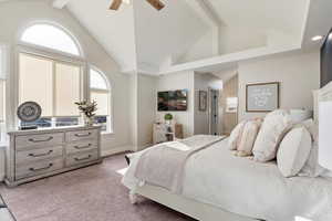 Bedroom with ceiling fan, light colored carpet, high vaulted ceiling, and multiple windows