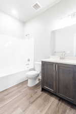 Full bathroom featuring washtub / shower combination, vanity, hardwood / wood-style flooring, and toilet