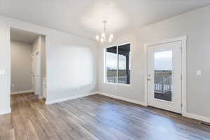 Unfurnished dining area featuring hardwood / wood-style floors and a notable chandelier