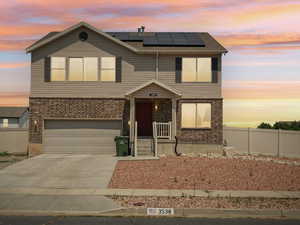 View of front of home featuring solar panels and a garage