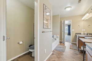 Bathroom with vanity, a tub to relax in, and toilet