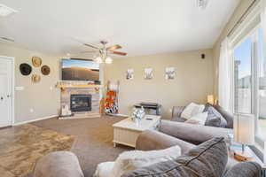 Carpeted living room with a fireplace and ceiling fan