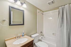 Full bathroom with vanity, shower / tub combo, and toilet