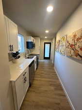 Kitchen featuring white cabinets, wood-type flooring, sink, and appliances with stainless steel finishes