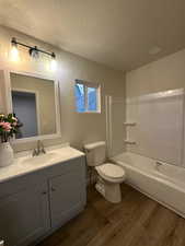 Full bathroom with toilet, vanity, a textured ceiling, and hardwood / wood-style flooring