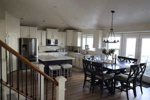 Dining area featuring dark hardwood / wood-style floors, sink, a chandelier, and vaulted ceiling