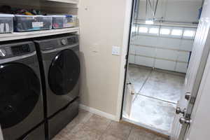 Washroom featuring washer and dryer and light tile patterned flooring