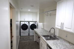 Laundry room with dark hardwood / wood-style floors, cabinets, separate washer and dryer, and sink