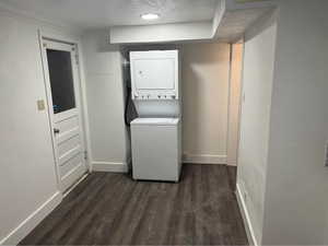 Laundry room with stacked washer / drying machine and dark hardwood / wood-style floors