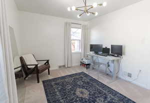 Office space featuring light carpet and an inviting chandelier