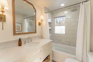 Full bathroom featuring vanity, toilet, and shower / bathtub combination with curtain