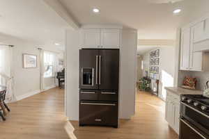 Kitchen featuring light wood-type flooring, stainless steel appliances, and white cabinetry