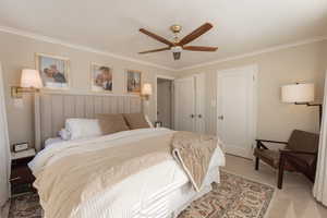 Bedroom with ceiling fan, light colored carpet, and ornamental molding