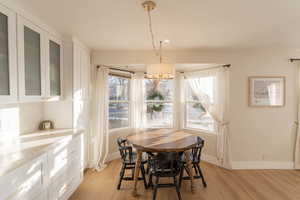 Dining area with light hardwood / wood-style flooring and an inviting chandelier